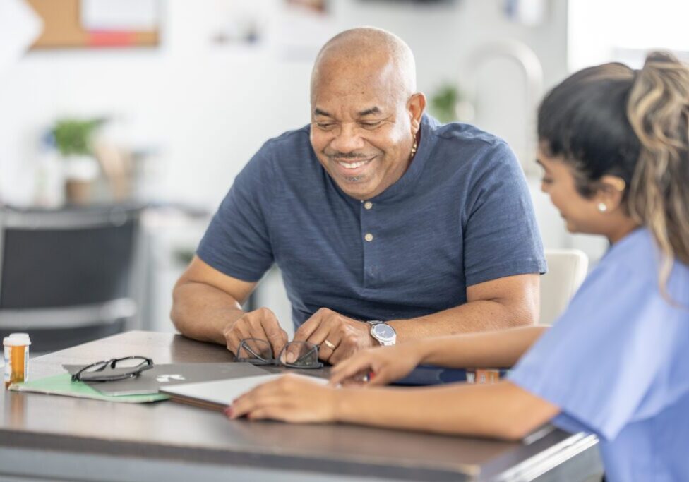 Man and nurse reviewing information at table.
